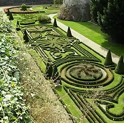 Photographie de jardins à la française, vue en plongée ; des buissons au premier plan.