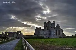 Photographie couleur d'un monastère partiellement ruiné sous un ciel nuageux