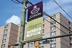 Photographie d'une bannière de rue sur laquelle on peut lire « Scranton » et « Dunder Mifflin ».
