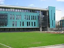 Photographie d'un bâtiment couleur turquoise, de la pelouse au premier-plan.