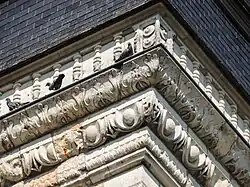 Vue rapprochée du décor sculpté de la corniche moulurée.