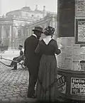 Passants consultant les programmes de théâtres sur une colonne d’affichage près du Burgtheater de Vienne en Autriche, photographiés par Emil Mayer au début du XXe&nbsp;siècle.