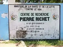 vue du mur à droite du portail d'entrée de l'institut montrant une peinture naïve, un peu délabrée, qui donne toutes les coordonnées de l'établissement