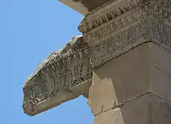 Frise de palmes et de roseaux stylisés alternés, et corniche décorée de moulures « en oves et dards ».