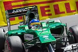 Photographie d'une monoplace de Formule vert foncé, en gros plan, de face.