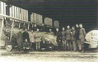 Photo noir et blanc d'un groupe d'hommes autour d'un avion biplan