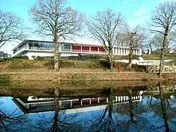 Photographie en couleurs de l'arrière du bâtiment se reflétant dans l'étang de Poulvern.