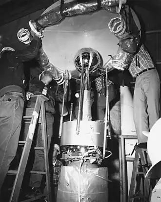 Explorer 10 fixé au sommet de la fusée Thor Delta est placé provisoirement sous une bâche.