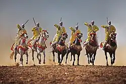 Groupe de cavaliers hommes en ligne et au galop.