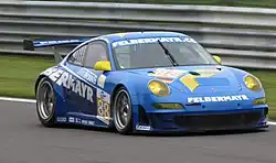 Photographie d'une voiture de grand tourisme bleue, blanche et jaune, vue de trois-quarts avant, sur une piste.