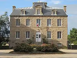 Photographie d'un bâtiment en granit à deux étages, surmontés d'un toit à lucarnes.