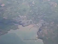 Photo à très haute altitude montrant deux agglomérations sur le pourtour d'une baie. La mer est au bas de l'image.