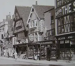 Ancienne photographie du bâtiment Tudor en bois et ses étages supérieurs en sailie.