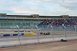 Scène de la course de Formule E de Berlin. Trois voitures sont dans un virage.