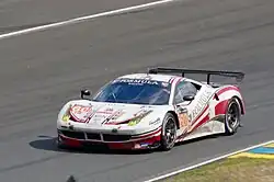 Photo d'une voiture blanche et rouge sur une piste de course.