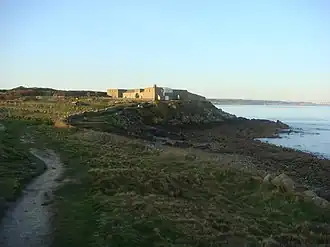 Vue d'un fort construit sur un petit promontoire rocheux, surplombant la mer.