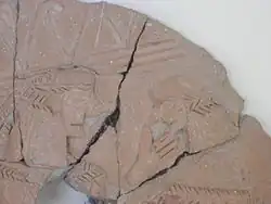 photo couleurs : fragment de poterie avec des figures humaines en relief.