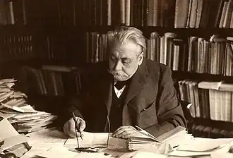 Photographie en noir et blanc d'un homme travaillant à son bureau.