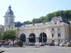 Vue d’un bâtiment blanc à trois arches, orné d’une tour.