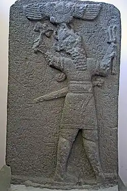 Stèle hittite tardive, basalte, 700-750 av. J.-C. Le dieu de la tempête Tysup tient une hache et un faisceau d'éclairs. Au-dessus du dieu, disque solaire ailé.