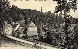Carte postale sépia représentant un bâtiment au bord d'un cours d'eau caché par des arbres.