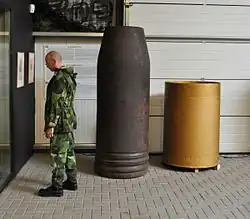 Une ogive dépourvue de sa cloche, tête percutante et explosive, et une douille du canon Krupp de 800&nbsp;mm.