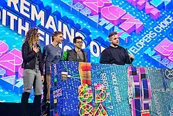 Quatre jeunes adultes sur une scène colorée.