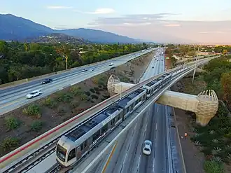 Rame de métro vue du ciel, au-dessus d'une autoroute.