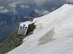 Deux refuges à la limite d'une arête neigeuse et de la paroi rocheuse.