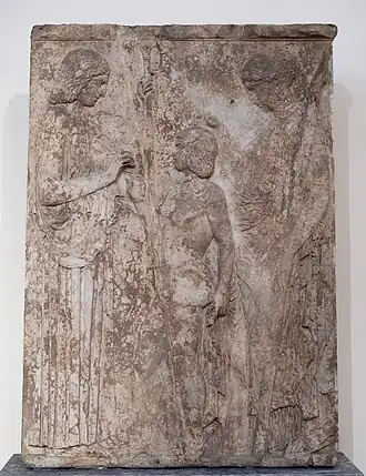 Stèle en marbre représentant deux femmes encadrant un homme.