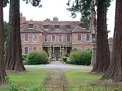 Photo : manoir de brique au bout d'une allée bordée de cèdres