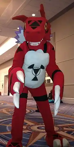 Photo d'une personne déguisée en une sorte de dinosaure rouge et blanc.