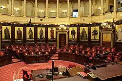  Vue de l'hémicycle du sénat belge depuis la tribune du président. Dans le fond de l'hémicycle, on voit neuf des quinze peintures historiques de Gallait qui décorent le pourtour du sénat belge. Les quinze peintures furent réalisées de 1872 à 1877. Sur la vue, on voit de gauche à droite: Philippe d'Alsace, Jean II duc de Brabant, Guillaume le Bon, Philippe le Noble, Philippe le Bon, Charles Quint, l'archiduchesse Isabelle, l'archiduc Albert, l'impératrice Marie-Thérèse.