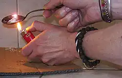 Un homme fait chauffer de l'héroïne dans une cuillère à l'aide d'un briquet.