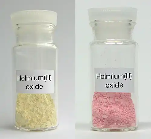 Ho2O3 vu sous lumière visible à gauche et sous tube fluorescent à droite.