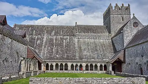 Photographie d'un cloître terminé par une église intacte.