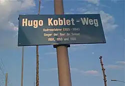 Photographie d'un panneau de rue bleu portant des inscriptions blanches.