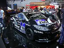 Photo d'une voiture de course de couleur noire, portant le numéro 200, dans un salon automobile.