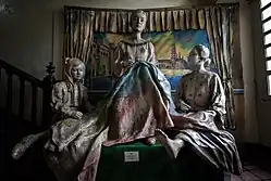 Deux femmes et une enfant assises, toutes tissant un drapeau étendu sur leur genou.