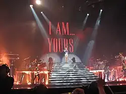 un concert, la chanteuse est en haut d'un grand escalier