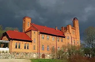 Photographie en couleurs d'une bâtisse illuminée de lumière chaude, se détachant sur fond de nuages gris