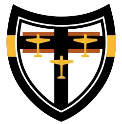 Emblème d'une unité de combat allemande avec la silhouette de trois avions jaunes sur une croix noire et un fond blanc.