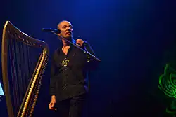 Alan Stivell sur scène au chant à côté de sa harpe celtique.