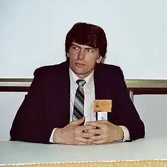 photographie couleur d'un homme assis derrière une table