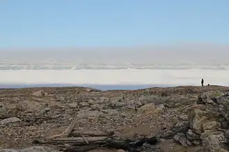 Photographie de Kvitoya, regardant vers le haut des montagnes depuis l'étroite bande de plage rocheuse. Elle fut prise juste à gauche du monument d'Andrée.