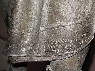  Partie d'une statue avec une inscription.