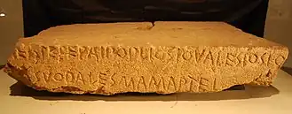 Le Lapis Satricanus. Document épigraphique sous forme de linteau de pierre écrit en latin archaïque. Artéfact attribué au tournant du VIe&nbsp;siècle&nbsp;av. J.-C. et du Ve&nbsp;siècle&nbsp;av. J.-C. Extrait en 1977, lors des fouilles archéologiques du Satricum, actuellement exposé au musée des Thermes de Dioclétien. Ce vestige est également l'une des rares occurrences matérielles témoignant des événements de l'an 509 à Rome.