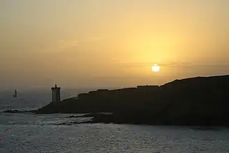 Silhouette de la presqu'île et du phare de Kermorvan lors d'un coucher de soleil.