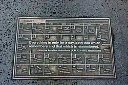 Plaquette en métal au sol sur laquelle on peut lire, en anglais, everything is only for a day both that which remembers and that which is remembered.