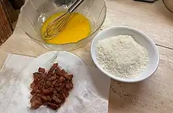 Photo d'œufs battu dans un saladier, de fromage râpé dans une assiette creuse et de morceaux de viande dans une assiette